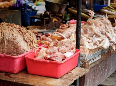 Geleneksel Endonezya sulak pazarında kırmızı plastik kaplarda sergilenen çiğ tavuklar ve taze tavuk sakatatı. Otantik pazar atmosferi olan yerel kasap tezgahı..