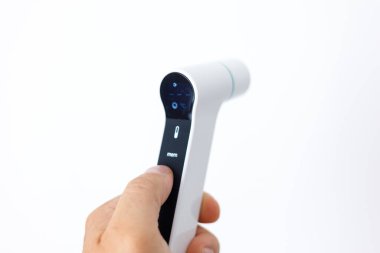 Beyaz arka planda kızılötesi dijital termometreyi tutan bir elin yakın çekimi. Akıllı sağlık, hijyen ve modern tıp teknolojisi kavramı.