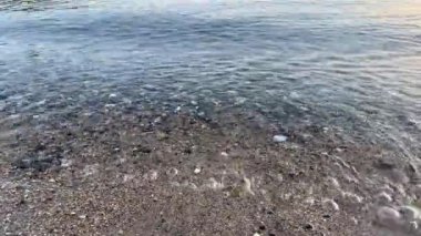 Gün doğumunda yumuşak sabah dalgalarıyla berrak deniz suyu. Sakin ve şeffaf deniz sahnesi yumuşak dalgalar, yüzeyin altında küçük çakıl taşları ve barışçıl ışık yansıması. Rahatlama ve doğa projeleri için mükemmel.