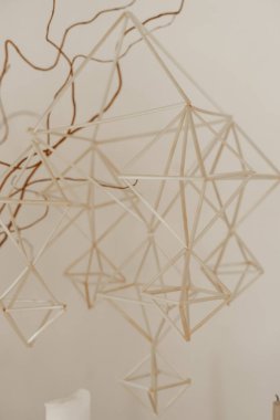 Hassas saman piramitleri geleneksel bir Fin himmeli süsü oluşturuyor. Minimum bej alanda kavisli dallardan sarkan yumuşak ışık konforlu tatil sezonluk iç dekorasyon sanatını yansıtıyor.