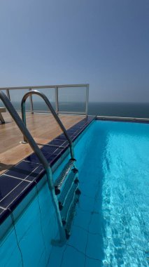 Durgun havuz suyu ve uzak okyanus, berrak yaz günışığında sakin ve sakin bir zihin oluşturur. Yumuşak dalgalanmalar, minimum geometri ve huzurlu sahil sessizliği.