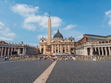 Vatikan 'daki Aziz Peter Meydanı' nın tam panoramik manzarası büyük bazilika cephesini, Michelangelo 'nun kubbesini, Mısır dikilitaşını, Bernini' nin sütunlarını ve kaldırım taşı plazasında turistleri gösteriyor..