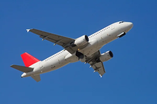 Airbus A-320 in vlucht tegen een blauwe hemel — Stockfoto