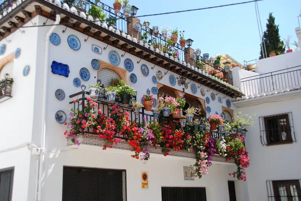 Кованый железный балкон на традиционном испанском таунхаусе с разнообразными цветами и украшенными тарелками в районе Альбайцин, Гранада . — стоковое фото
