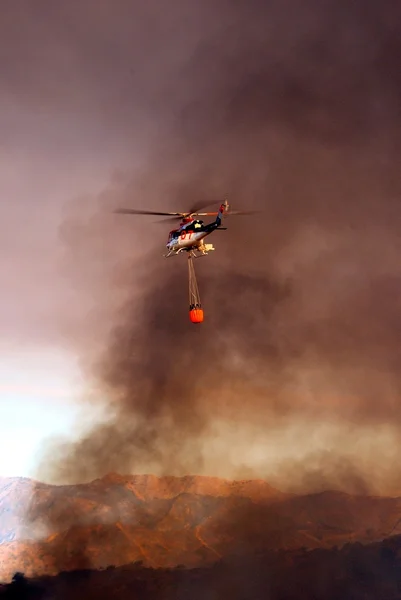 Bell 412 helicopter (registration N167EH) taking water to brush fire, Spain. — Stock Photo, Image