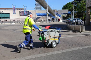 Çöp toplayıcı Millennium Place, Coventry de kaldırım boyunca onun arabası iterek.