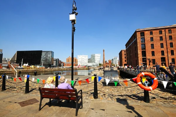 Duas senhoras sentadas em um banco olhando através de Canning Dock com The Pumphouse e cidade para trás, Liverpool . — Fotografia de Stock