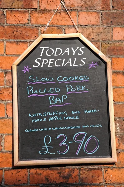 Todays Special chalkboard against a brick wall advertising Pulled Pork Bap.