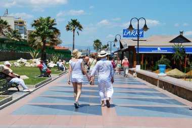 Sağ tarafta plaj barları ile gezinti boyunca yürüyen turistler, Benalmadena.