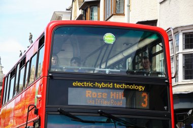Red electric-hybrid bus along High Street, Oxford. clipart