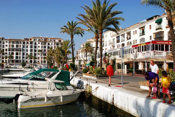 Yates y barcos en el puerto deportivo rodeado de apartamentos y restaurantes y una familia en primer plano alimentando a los peces, Puerto Duquesa . — Foto de Stock