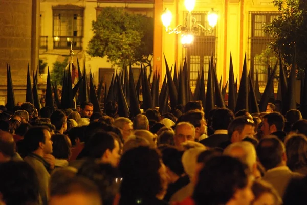 Miembros de la hermandad de La Bofeta caminando por las multitudes alrededor de la Catedral durante la noche de Santa Semana, Sevilla . — Foto de Stock