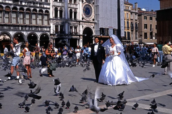Noiva e noivo caminhando por uma praça de St Marks lotada, Veneza . — Fotografia de Stock