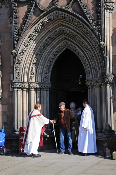 Clergyman greeting members of the congregation outside the Cathedral West Front door, Lichfield.