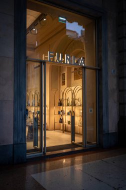 Milan, İtalya - 2026, 13 Ocak: FW25 ekran aydınlatmalı şık Furla butiği, modern cam giriş ve sofistike iç mekan, lüks ve İtalyan tarzını ön plana çıkarıyor