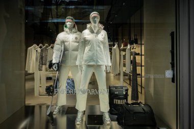 Milan, İtalya - 2026, 3 Şubat: Emporio Armani FW25 vitrininde modern bir butik ortamda beyaz kayak esinlenilmiş kıyafetler, lüks aksesuarlar ve zarif kış modası yer almaktadır.