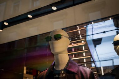 Milan, İtalya - 2026, 3 Şubat: Ferragamo FW25 vitrininde şık metalik bir ceket ve tasarımcı güneş gözlüğü sergileniyor.