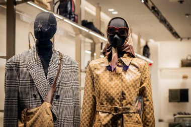 Milan, İtalya - 2026, 3 Şubat: Gucci FW25 modern lüks bir butik ortamında şık desenli dış giyim ve şık aksesuarlar sergiliyor