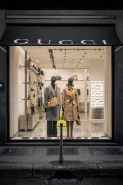 Milan, İtalya - 2026, 3 Şubat: Gucci FW25 butik vitrin vitrininde zarif mankenler, lüks aksesuarlar ve sofistike bir şehir ortamında modern moda eğilimleri yer alıyor.