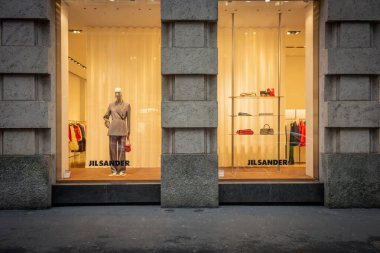 Milan, İtalya - 2026, 3 Şubat: Jil Sander FW25 butik vitrininde sofistike şehir ortamında minimalist lüks, şık gösteriler ve şık moda yer alıyor.