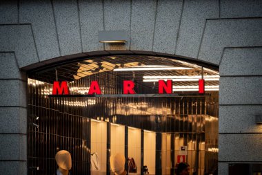 Milan, İtalya - 2026, 3 Şubat: Marni FW25 mağaza vitrininde koyu kırmızı tabela, modern mimari ve lüks bir şehir ortamında şık, aydınlık bir moda gösterisi