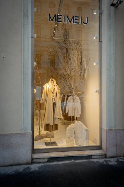 Milan, İtalya - 2026, 3 Şubat: Meimeij FW25 butik vitrin vitrininde, modern şehir ortamında minimalist zarafet, nötr tonlar ve sofistike moda yer alıyor.
