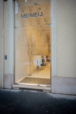 Milan, İtalya - 2026, 3 Şubat: Meimeij butik koleksiyonu minimalist cam mağaza önü, zarif iç mekan ve şık kentsel cazibe ile FW25 koleksiyonu sergiliyor