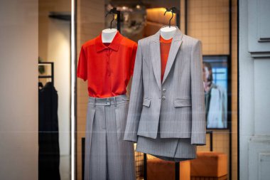 Milan, İtalya - 2026, 3 Şubat: Havalı Patrizia Pepe FW25 vitrininde şık bir butik mağazada özel dikim ceket, pileli etek ve kalın turuncu bluz sergileniyor