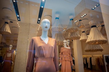 Milan, İtalya - 2026, 3 Şubat: Twinset FW25 butik vitrin vitrininde modern İtalyan moda eğilimlerini vurgulayan şık şeftali elbiseli zarif mankenler sergileniyor