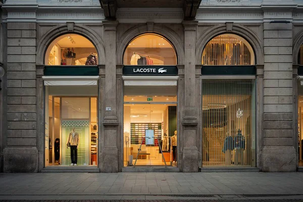 Milan, İtalya - 2026, 3 Şubat: Lacoste FW25 butiği ışıklı kemerli pencereler, zarif taş ön cephe ve lüks bir alışveriş bölgesinde şık moda sergileri