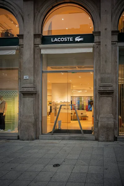 Milan, İtalya - 2026, 3 Şubat: Zarif taş cepheli Lacoste FW25 butiği, aydınlık giriş ve birinci sınıf bir moda bölgesinde canlı bir vitrin.