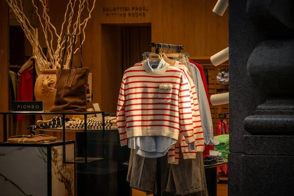 Milan, İtalya - 2026, 3 Şubat: OVS FW25 vitrininde çizgili bir kazak ve katmanlı bir kıyafet sergilenerek, modern Milano moda trendleri ve şık butik cazibesi vurgulandı