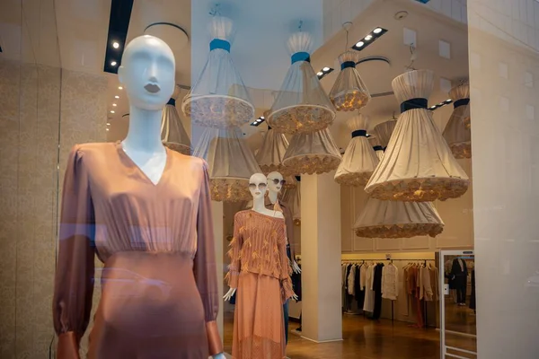 Milan, İtalya - 2026, 3 Şubat: Twinset FW25 butik vitrininde şık şeftali rengi ve desenli elbiselerle şık ve modern bir perakende iç mekanda geçen zarif mankenler ön plana çıkarıldı