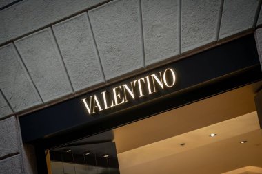 Milan, İtalya - 2026, 3 Şubat: Valentino FW25 butik girişi aydınlatmalı tabela, zarif taş cephe ve modern lüks tasarım moda-ileri şehir ortamında