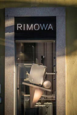 Milan, İtalya - 17 Şubat 2026: Rimowa SS26 bavulu lüks seyahat tarzı ve çağdaş moda eğilimlerinin vurgulandığı gösterişli, modern bir vitrin vitrininde sergilendi