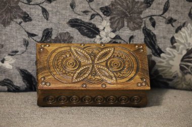 Light brown wooden rectangular box with handcrafted Christmas patterns on the lid. Central motif resembles a flower or star, blurred background emphasizes the bo