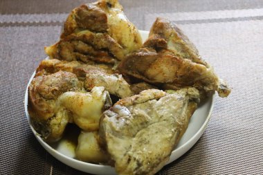 A large portion of baked meat with golden crust. Juicy pieces seasoned with spices, look appetizing.