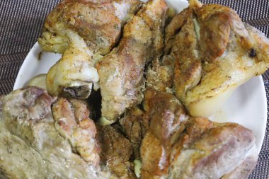 Cooked pork pieces on a white plate. Brownish surface with spices gives an appetizing look.