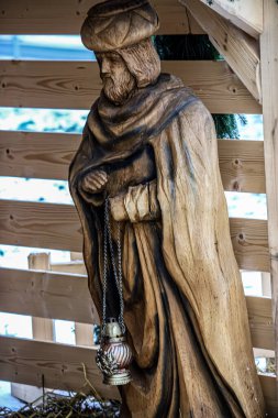 Ayrıntılı bir ahşap oyma, türbanla süslenmiş ve metal bir sandığı zincirle tutan Üç Bilge Adam 'dan birini tasvir ediyor.