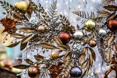Zengin metalik tonlarda takılar, yapraklar ve dalların yer aldığı bayram dekorasyonlarının yakın çekim görüntüsü