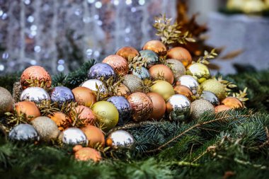 Altın, bakır ve gümüş renkli çeşitli Noel mücevherleri, çam iğneleri ve dekoratif yapraklarla ustalıkla düzenlenmiş yakın çekim görüntüsü.