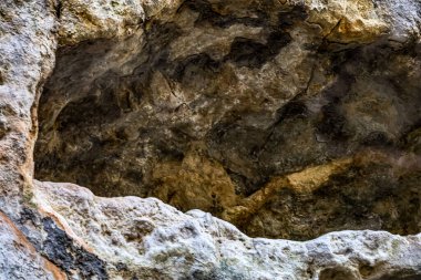 Doğal bir mağara açıklığı içindeki antik kaya oluşumlarının detaylı dokusu, toprak tonlarını ve sert yüzeyleri gösteriyor.