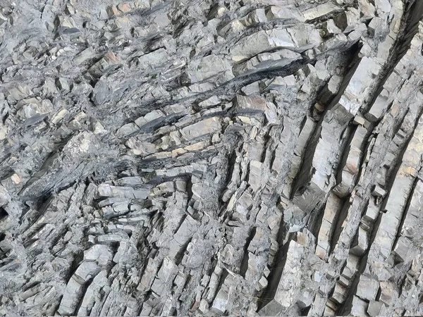 Jeolojik kıvrımlı katmanların taş dokusu. Çizgi karşıtı katlama.