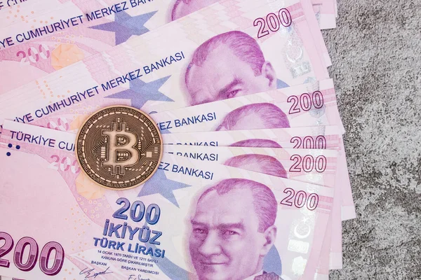 Arka planda Türk lira banknotları ve bitcoin para.