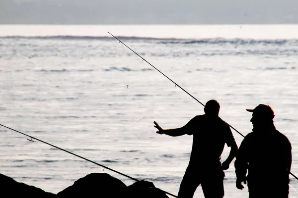 Siluetas Pescadores Aficionados Con Cañas Pescar Orilla Del Mar Temprano — Vector de stock