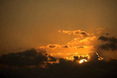 Altın Güneş ve Kara Bulutlar ile dramatik Günbatımı Gökyüzü. Yoğun, güzel doğa arkaplanı. Sıcak turuncu, altın ve koyu renkler. Karanlık, fırtınalı bulutlardan süzülen parlak güneşli dramatik ve yoğun günbatımı..