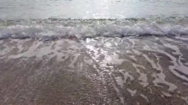 Kristal berrak okyanus dalgaları kumsala vuruyor. Gün batımında yumuşak şeffaf deniz dalgaları çakıllı bir sahilde süzülüyor. Huzurlu yaz kıyı doğası geçmişi.