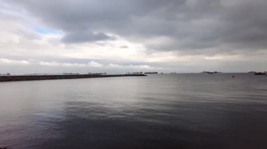 Bakirköy, İstanbul.Türkiye. 23 Aralık 2025. Bakırköy, İstanbul.Marmara Denizi 'ndeki bir rıhtımda deniz trafiği. İstanbul' da dramatik bulutlu gökyüzünün altında kargo gemileri ufukta belirdi..
