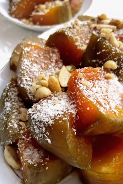 Geleneksel cevizli Türk Balkabağı Tatlısı. Lezzetli ev yapımı Kabak Tatlisi üzerine doğranmış hindistan cevizi ve ezilmiş fındık, beyaz bir tabakta servis ediliyor. Otantik Akdeniz tatlıları.