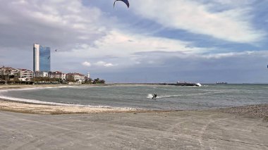 Yıldırım, İstanbul, Türkiye. 11 Ocak 2026.Uçurtmacılık İstanbul 'un Yesilkoy kentinde. Avrupa kıyılarında Marmara Denizi dalgalarında sörf yapan sporcular. Arka planda kargo gemileri olan manzaralı sahil manzarası..